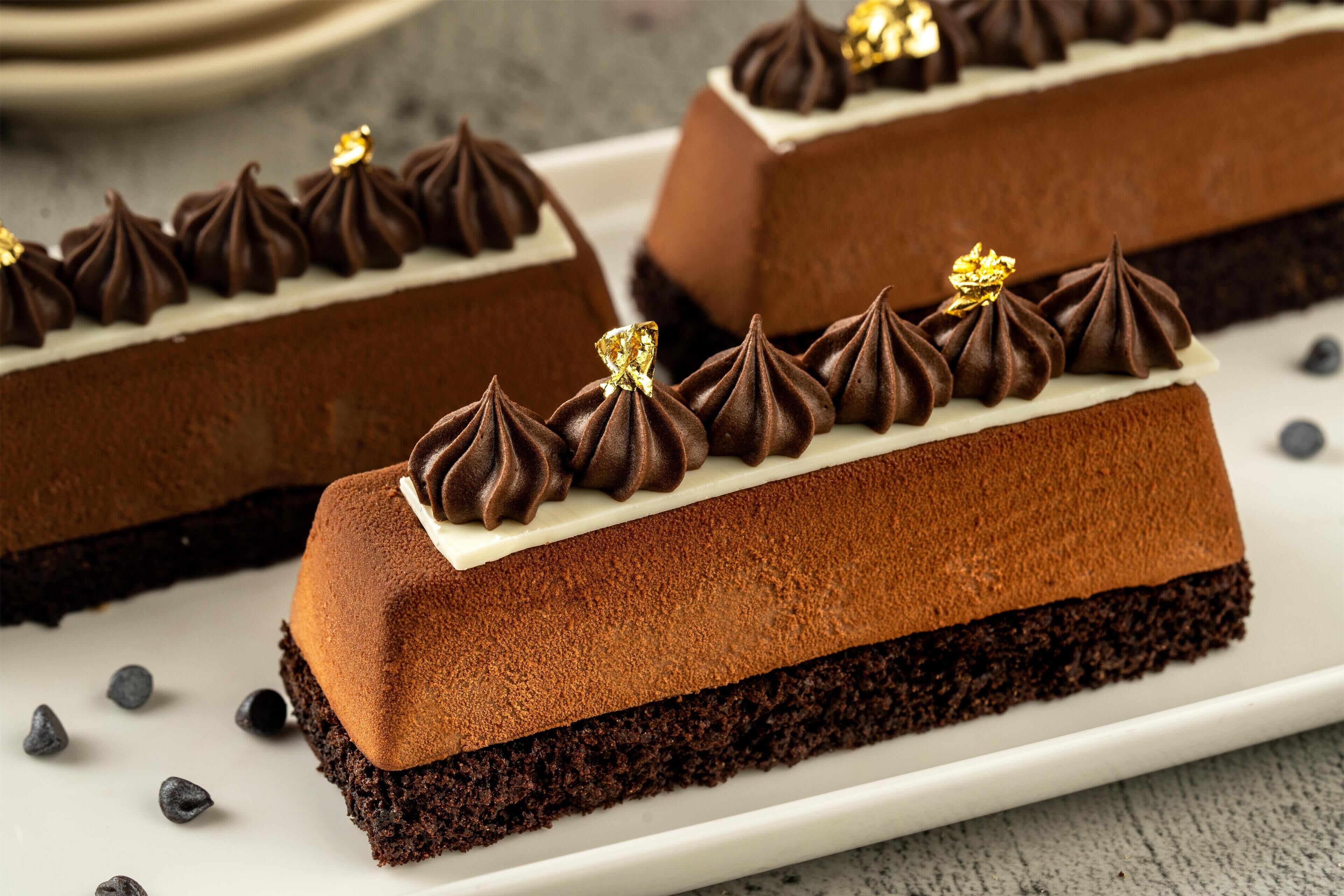 A chocolate cake with white frosting and decorative gold elements on top.