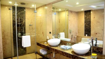 A modern bathroom with a glass-enclosed shower, two sinks, and a large mirror.