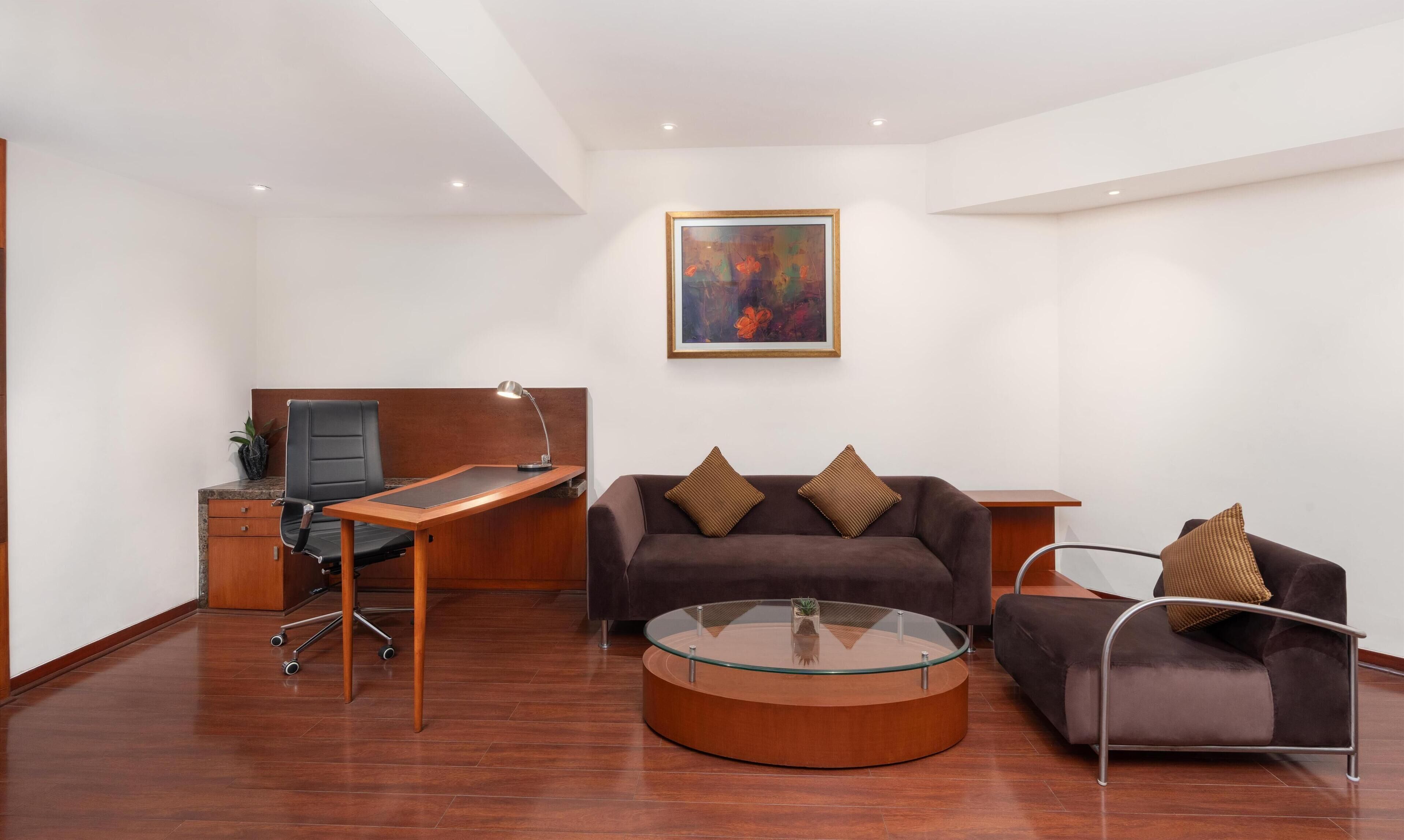 A modern office space with a desk, office chair, and a couch with cushions.