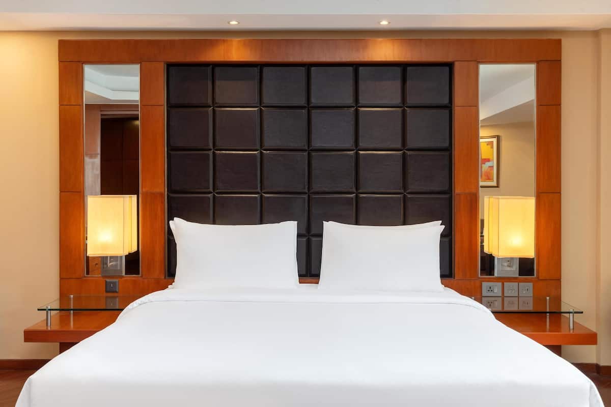 Una habitación de hotel con una cama grande, cabecero de madera y lámparas de noche.