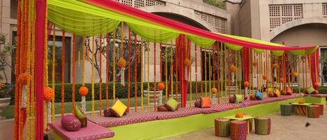An outdoor seating area with colorful drapes and cushions, set against a building facade.