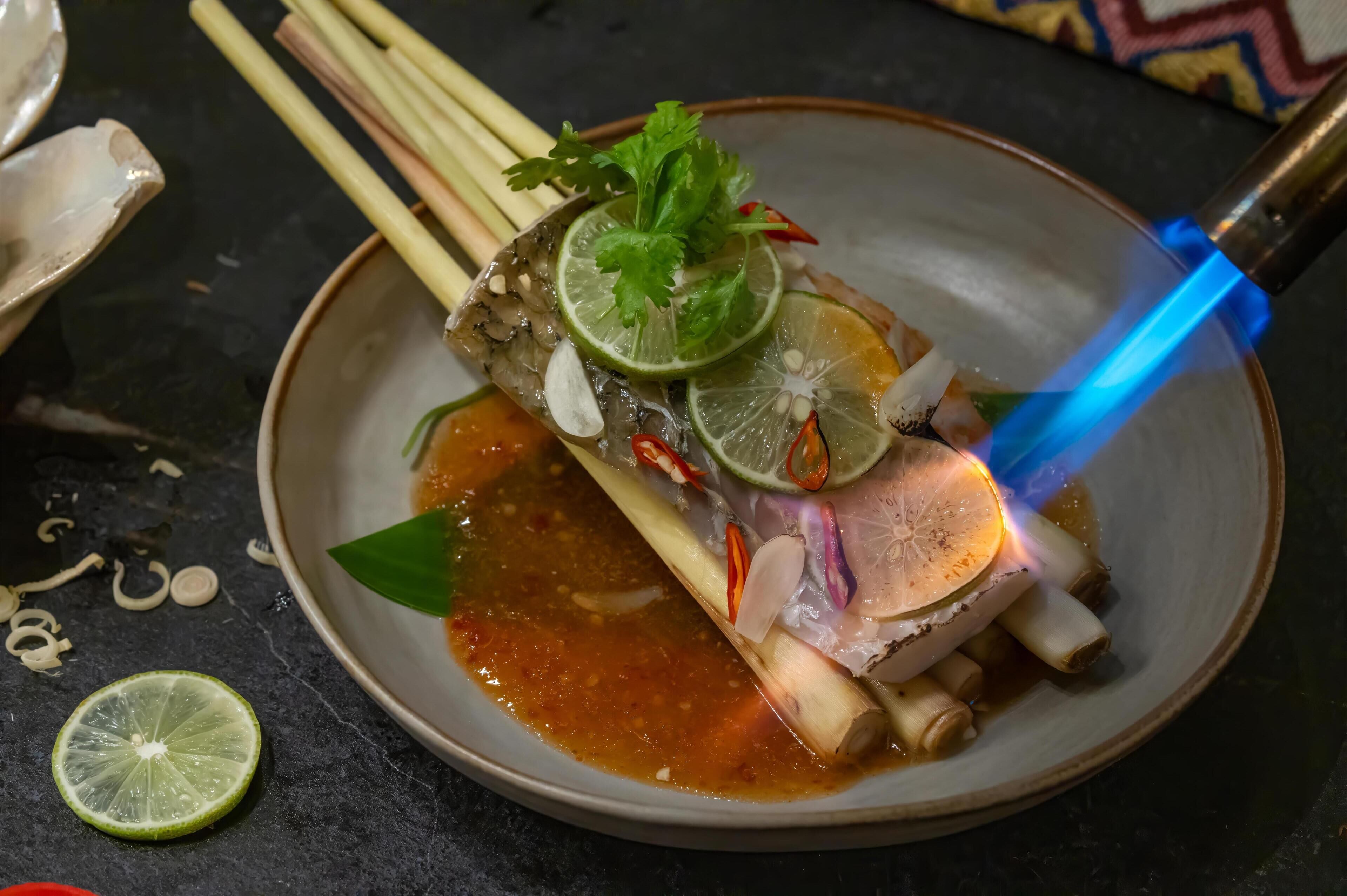 Un plat agrémenté d’une tranche de citron vert, de coriandre et de piments, le tout présenté sur une assiette éclairée d’une lumière bleue.