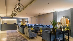 A modern hotel lobby with a reception desk, seating area, and decorative lighting. - The Ellison Hotel (Castlebar)