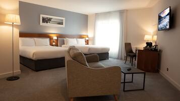 Ein Hotelzimmer mit einem großen Bett, einer Couch, einem kleinen Tisch und einem Fernseher.