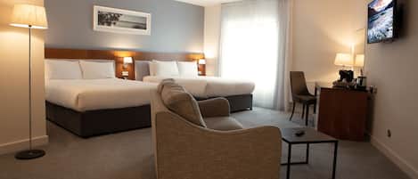 A hotel room with a large bed, a sofa, a small table, and a TV.