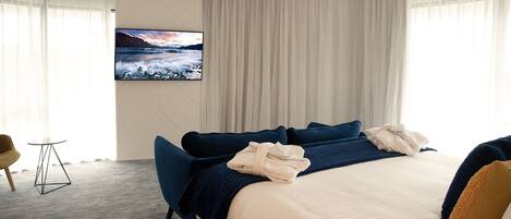 Une chambre d’hôtel avec un grand lit, un téléviseur fixé au mur, une petite table et une chaise.