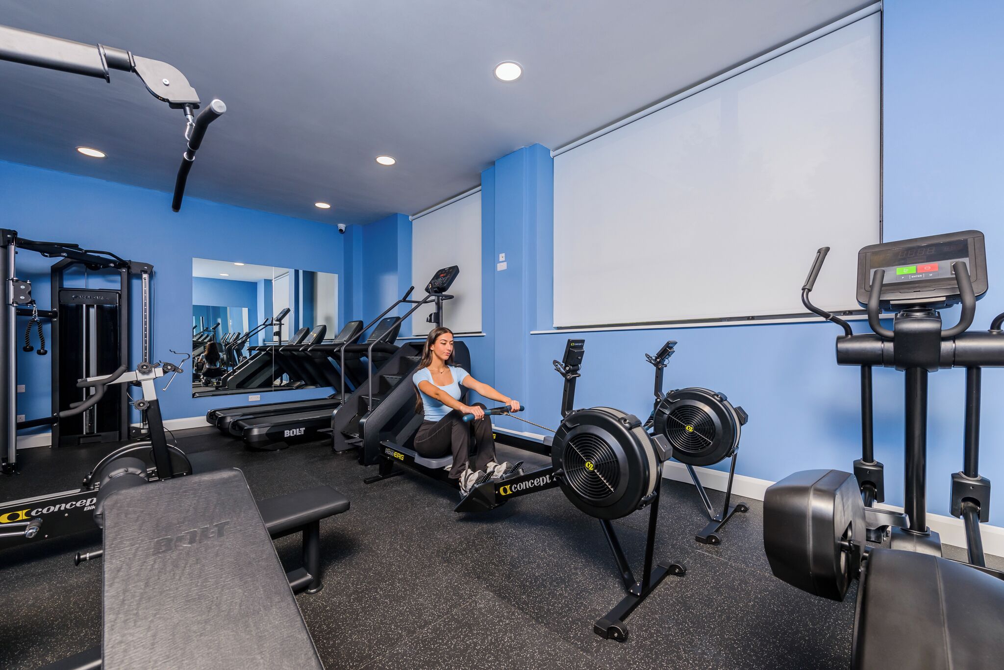 A gym with a rowing machine, treadmills, and weight machines.