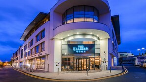 A modern hotel with a curved facade, a prominent entrance, and a neon sign for 'The Ellison'. - The Ellison Hotel (Castlebar)