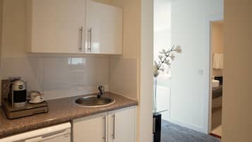 A modern kitchen with white cabinets, a granite countertop, and a coffee maker.