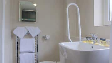 A bathroom with a white sink, a toilet, a towel rack with towels, a mirror, and a trash can.