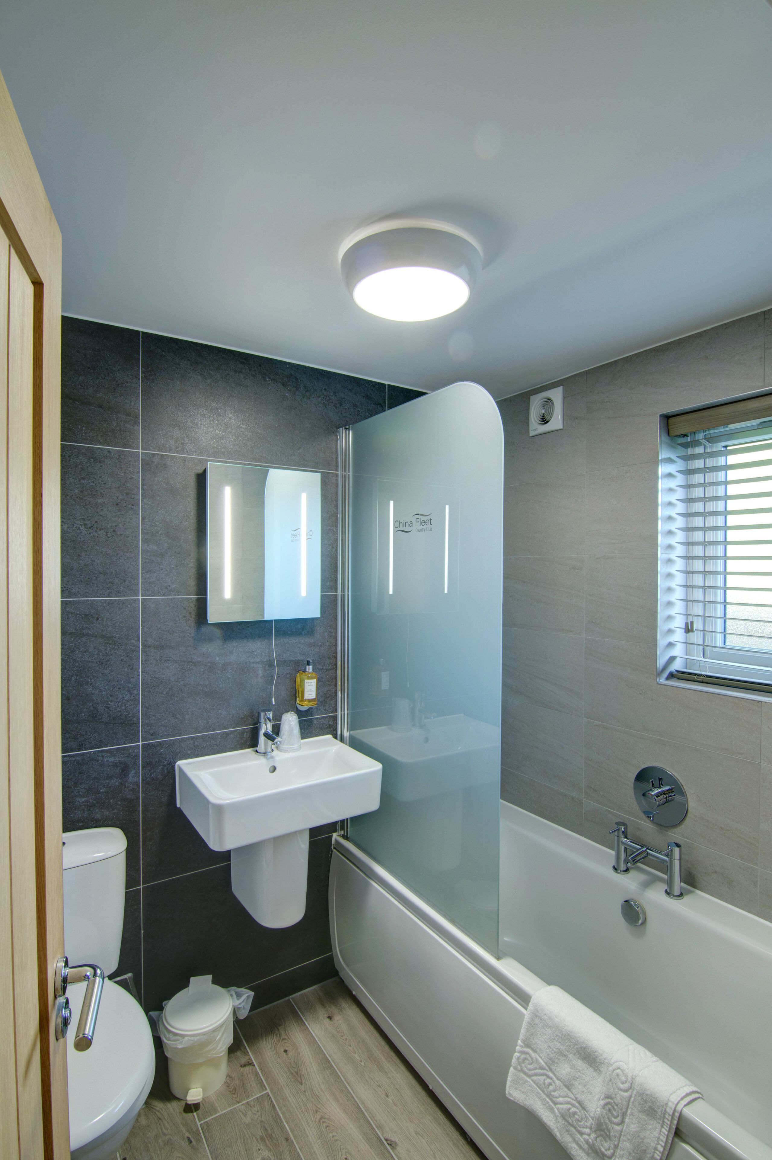 Un baño moderno con ducha de vidrio, lavamanos blanco y retrete.