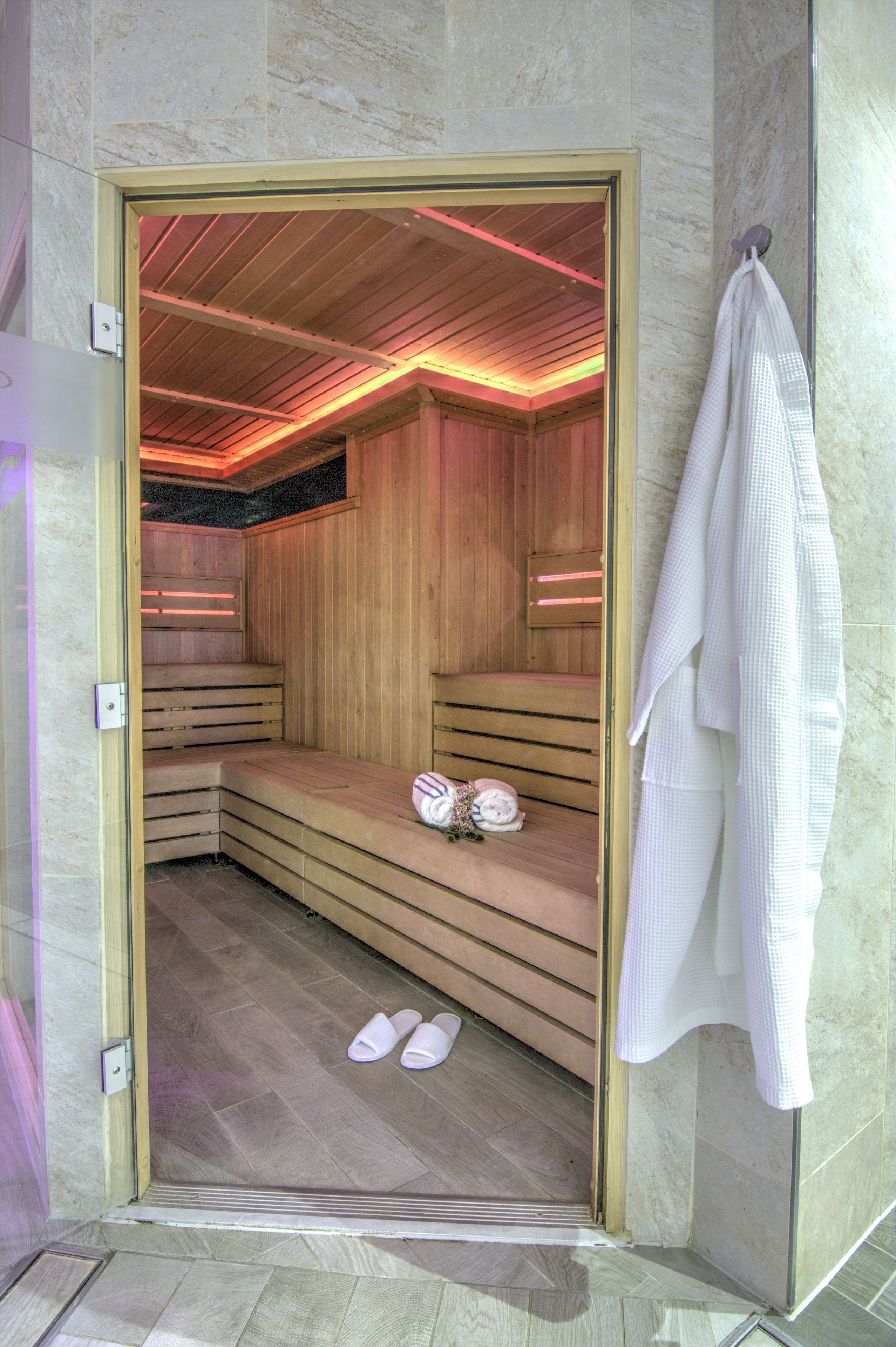 Un sauna avec des bancs en bois, ainsi qu’un banc muni d’une serviette et d’une paire de chaussons.