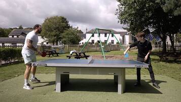 Deux personnes jouant au ping-pong dans un parc en plein air.