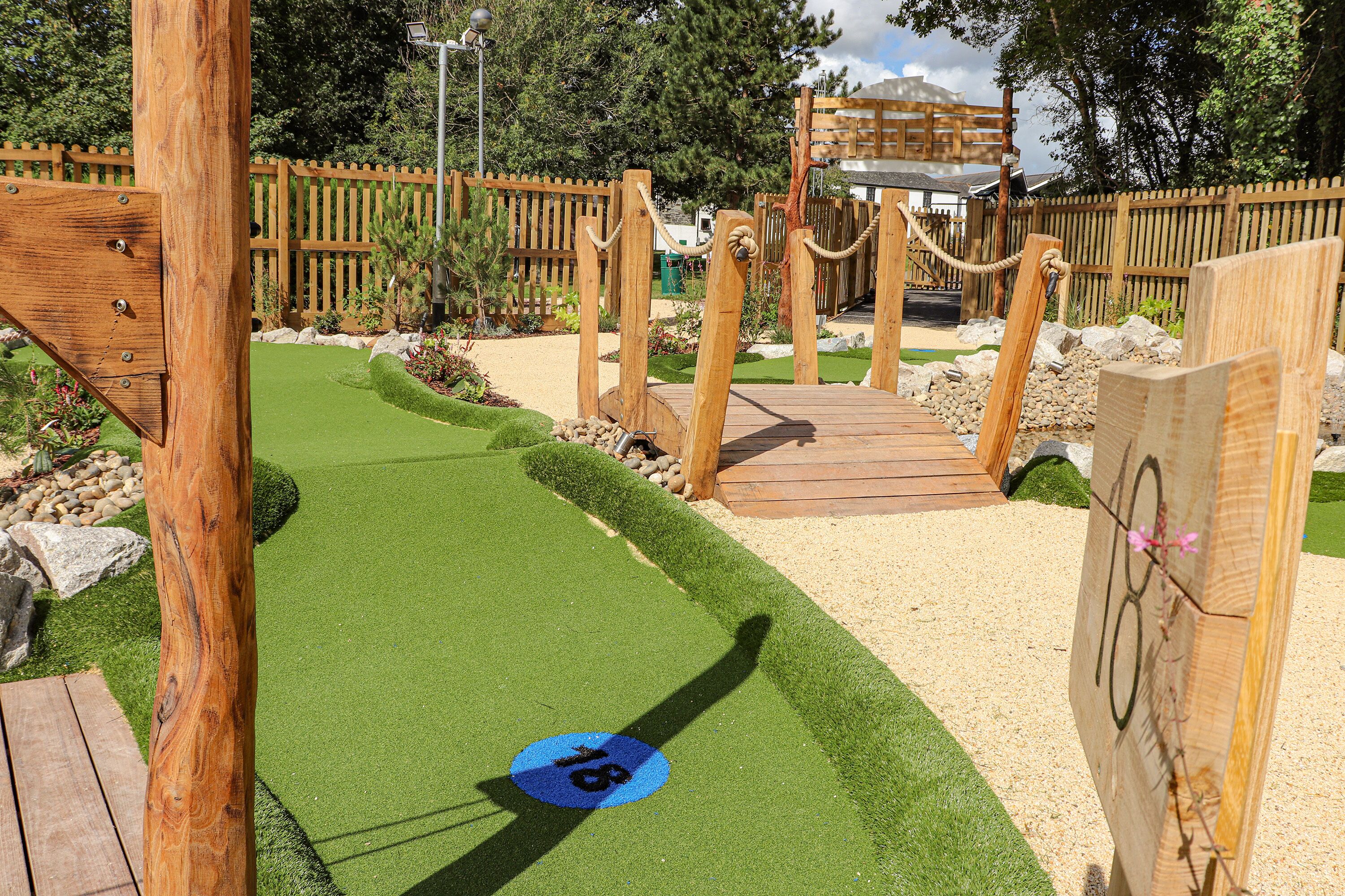 A wooden bridge over a green artificial turf with a blue circular marking.