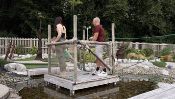 A wooden platform over a small pond with a rope barrier, surrounded by rocks and greenery.