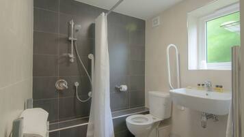 A bathroom with a shower, toilet, sink, and a window.