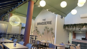 A restaurant interior with tables and chairs, a sign reading "THE BRASSERIE", and hanging lights. - China Fleet Country Club (Saltash)