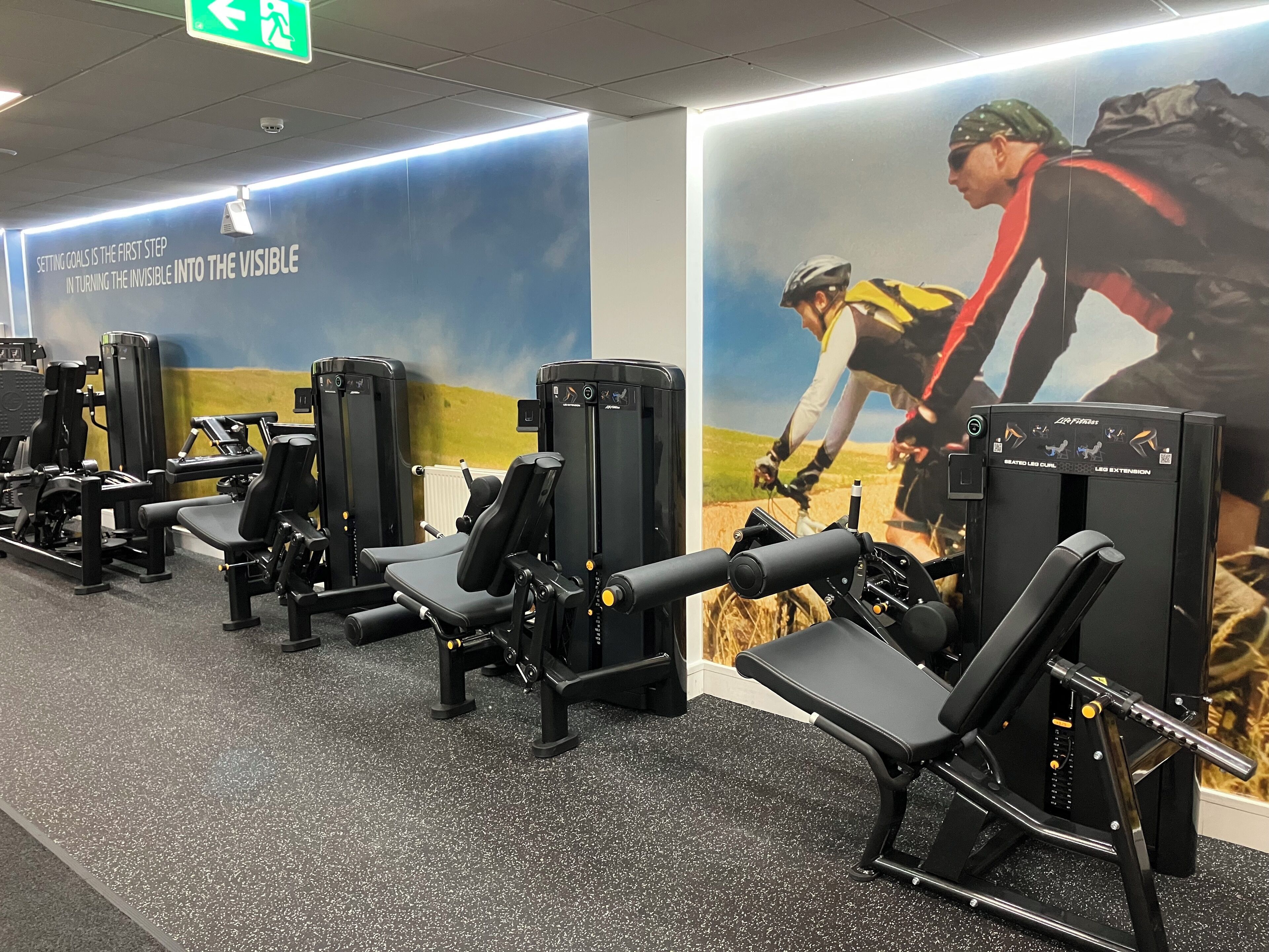A gym with exercise equipment and motivational posters on the walls.