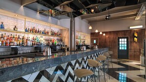 Zona bar dal design moderno, con pavimento a motivi a zigzag, sgabelli da bar e una selezione di bottiglie di liquori.