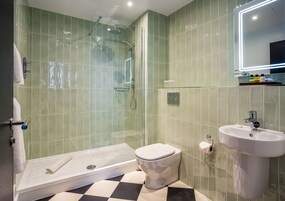 Un baño moderno con ducha de vidrio, inodoro blanco y lavamanos con espejo.