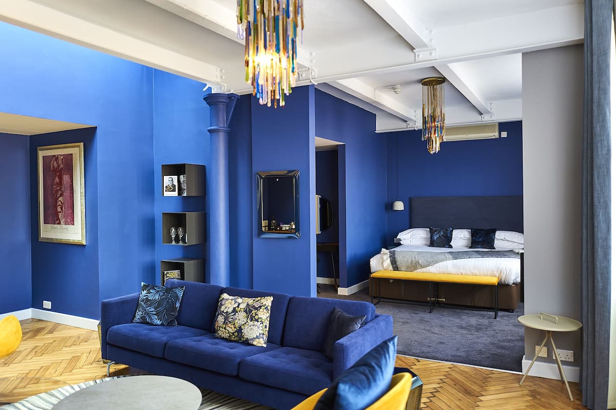 A modern living room with a blue sofa, a small round table, and a wooden floor.