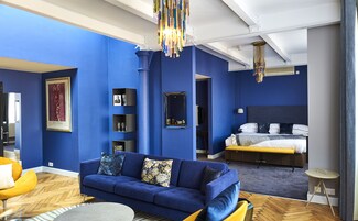 Una sala de estar moderna con un sofá azul, una mesita redonda y piso de madera.