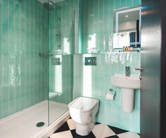 A bathroom with a glass-enclosed shower, a white toilet, and a sink with a mirror above it.