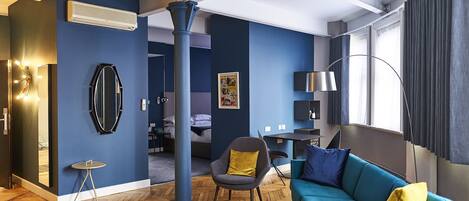 Un salon moderne avec un mur bleu, un canapé, un fauteuil et une table à manger.