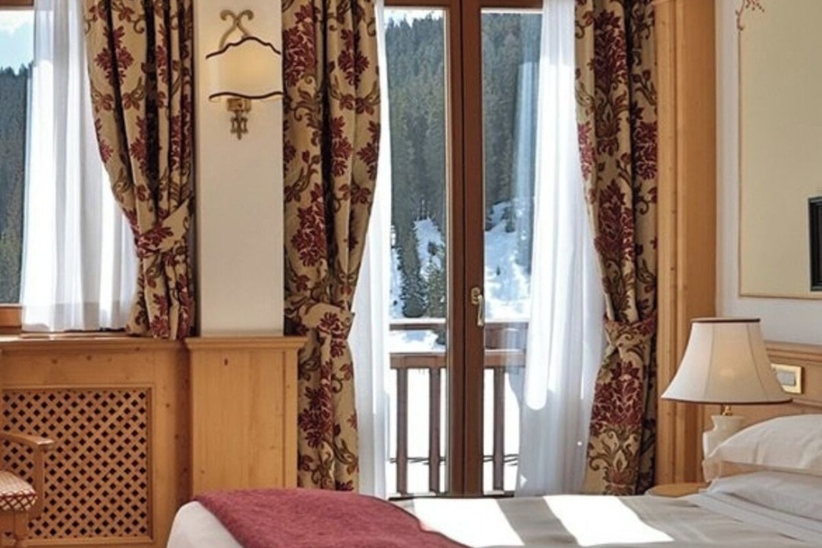 Habitación de hotel con cama, escritorio y vista a un paisaje nevado a través de la ventana.