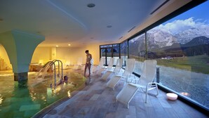 Piscina interior moderna con vistas despejadas a montañas a través de amplios ventanales.