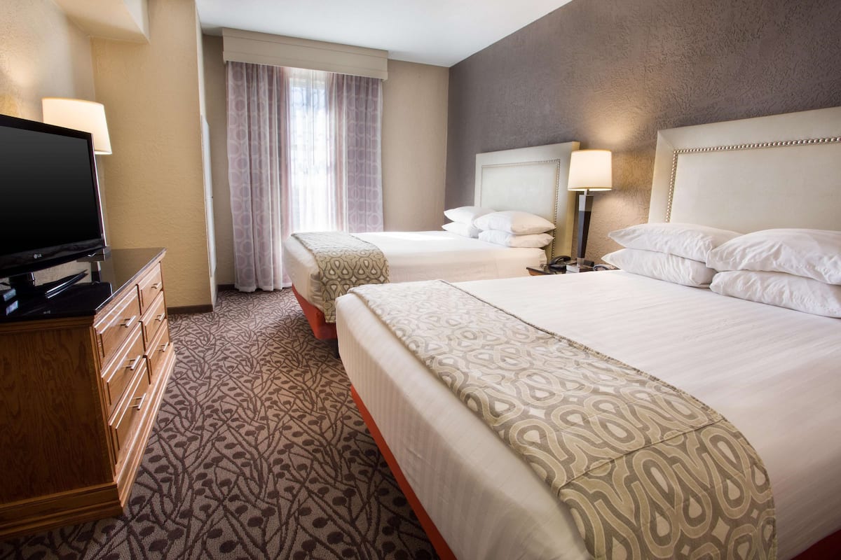 A hotel room with a large bed, a smaller bed, a TV, and a dresser.