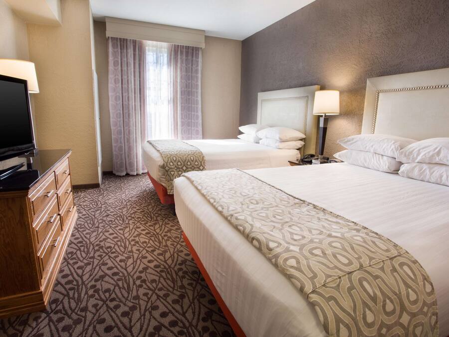 A hotel room with a large bed, a smaller bed, a TV, and a dresser.