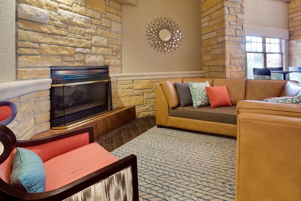 A living room with a stone fireplace, a sofa set, and a patterned rug.