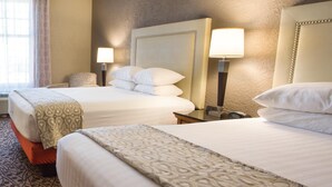 A hotel room with two beds, each with a headboard, bedside lamps, and a patterned throw blanket. - Drury Inn & Suites Amarillo (Amarillo)