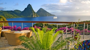 A terrace with wicker furniture, a view of the sea, and a ship in the distance. - Jade Mountain Resort (Soufrière)