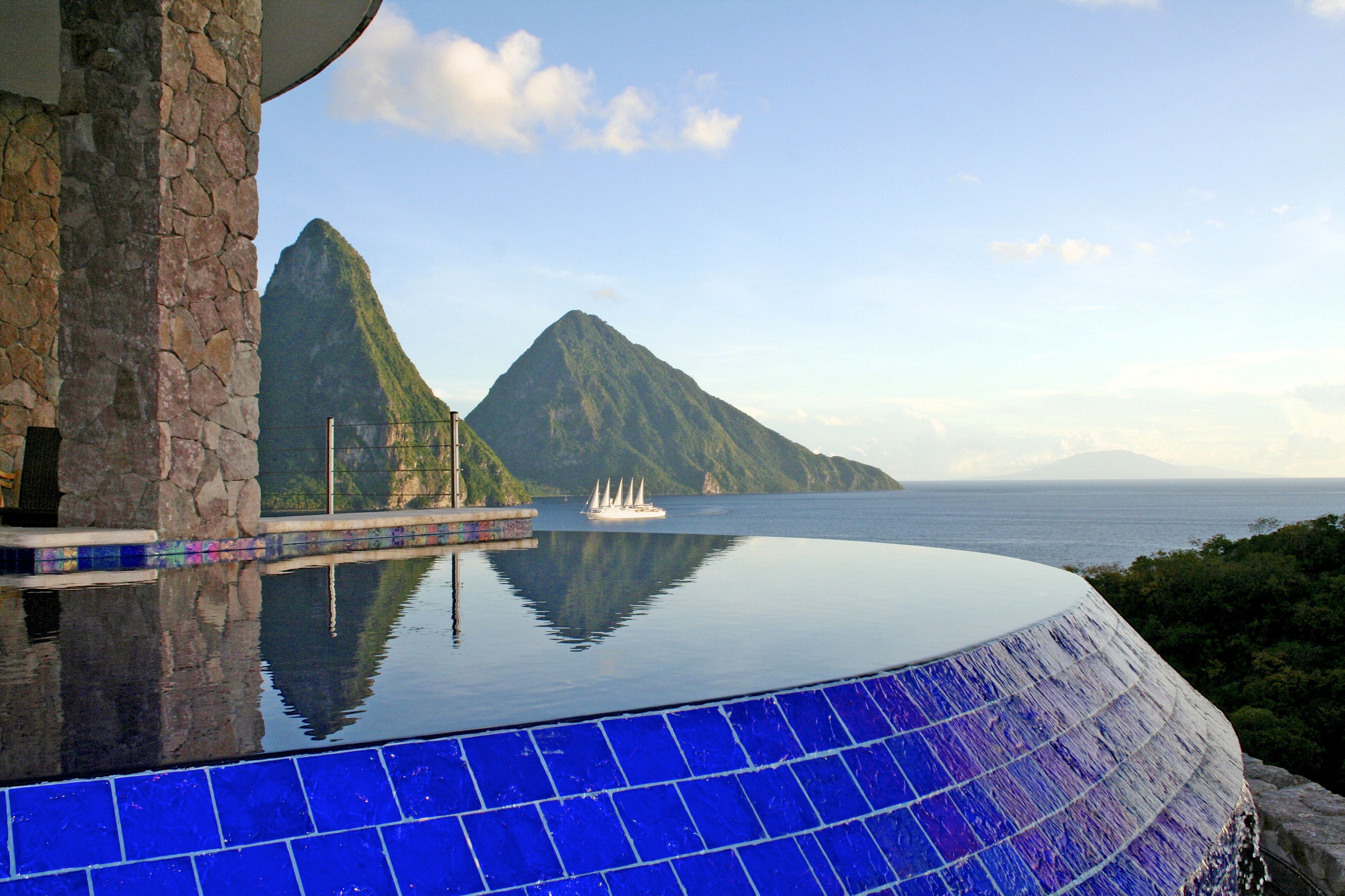 A infinity pool with a view of a mountain and the sea.