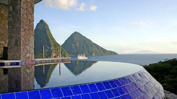 A infinity pool with a view of a mountain and the sea.