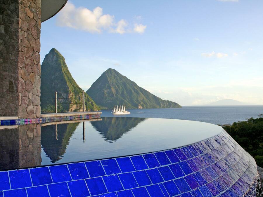 A infinity pool with a view of a mountain and the sea.
