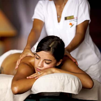 A massage therapy session in progress with a client lying face down on a massage table, receiving attention from a therapist.