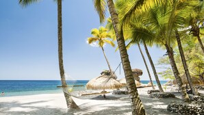 A beach with palm trees, a hammock, and a thatched hut. - Jade Mountain Resort (Soufrière)