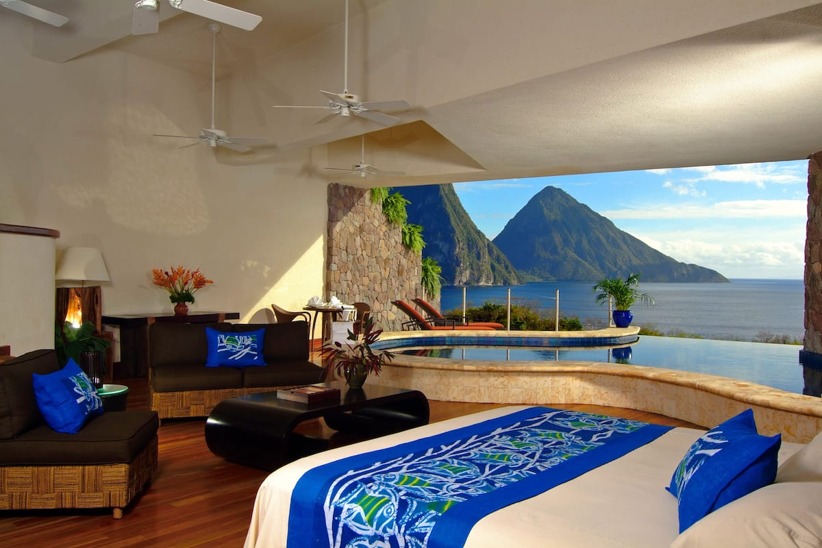 Un dormitorio con una cama grande, vistas a un paisaje montañoso, una piscina y un comedor con vistas.