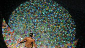 A person sitting in a circular pool with a mosaic tile floor.