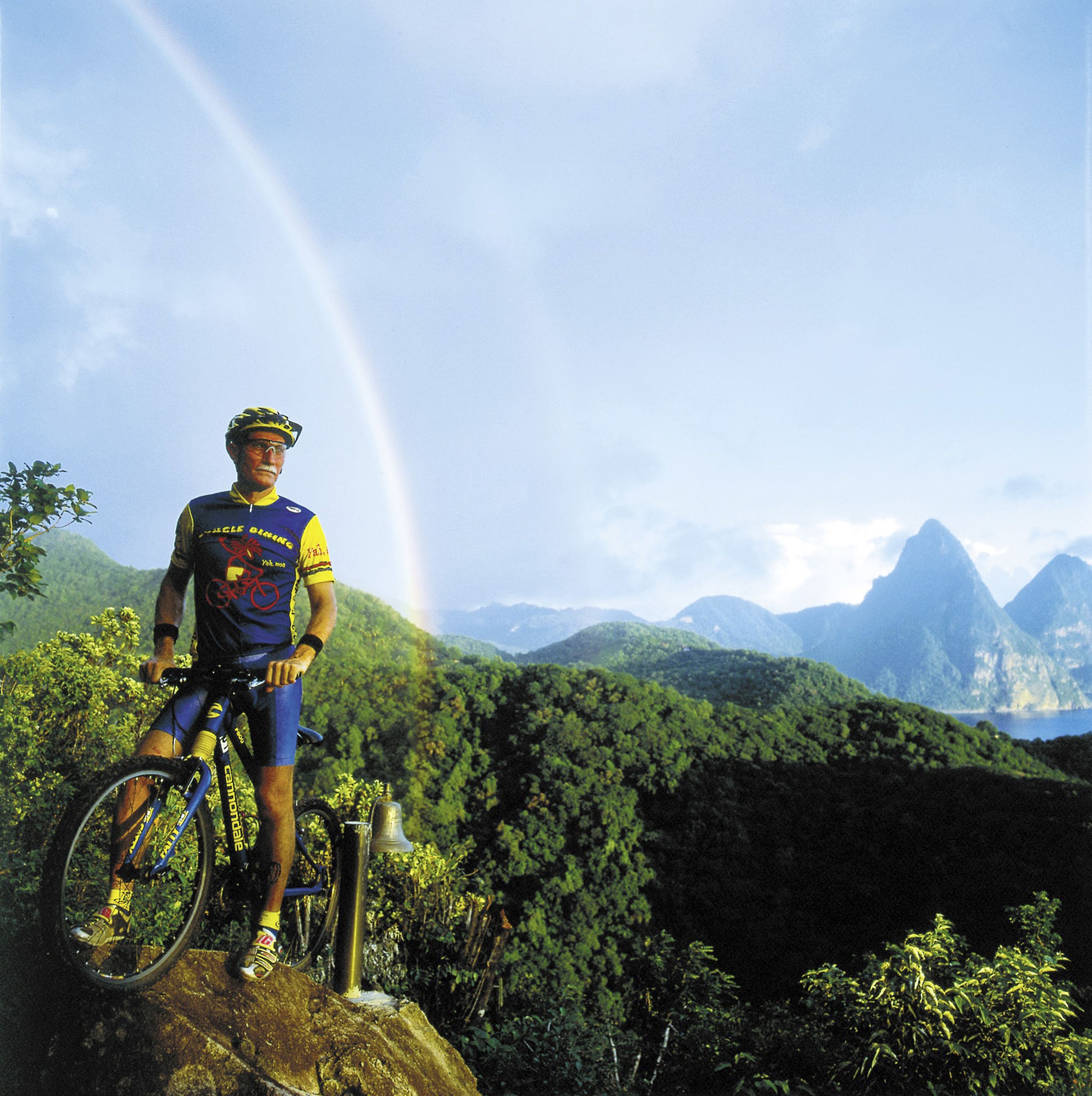 A cyclist on a mountain bike with a rainbow in the background.
