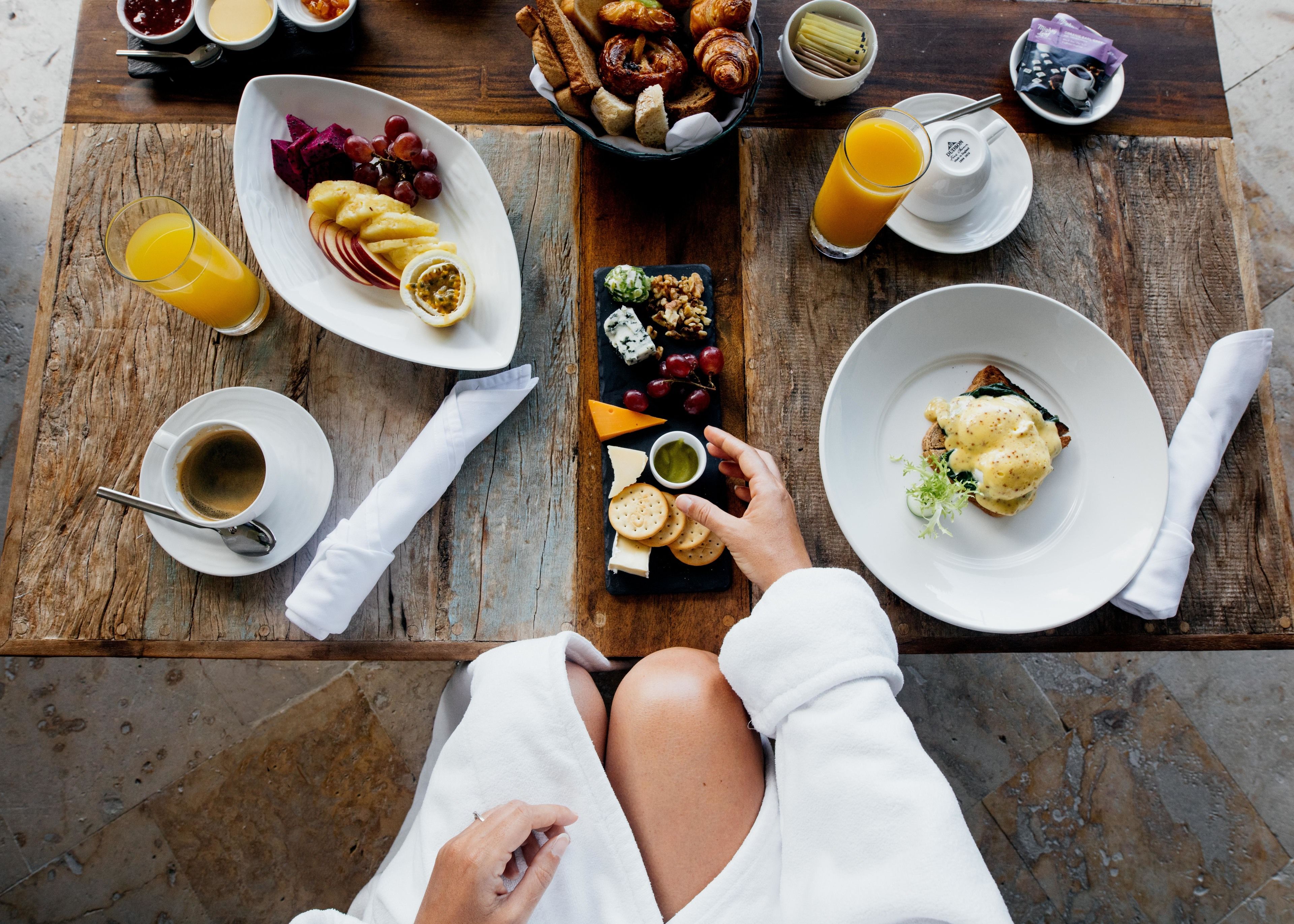 A breakfast table with various food items, a glass of orange juice, and a cup of coffee.