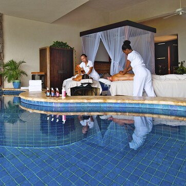 A spa area with a stone wall, a pool, and a massage table.