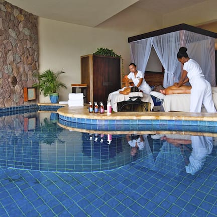A spa area with a stone wall, a pool, and a massage table.