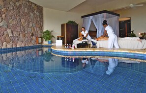 A spa area with a stone wall, a pool, and a massage table.