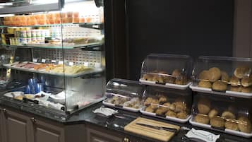 Buffet com diversos alimentos, incluindo pastéis e sanduíches, expostos em recipientes transparentes.