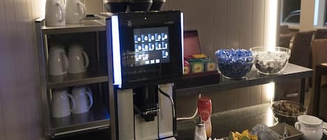 A coffee station with a coffee machine, cups, and various condiments.