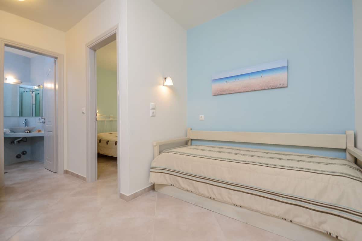 A bedroom with a bed, a bathroom with a sink, and a painting on the wall.
